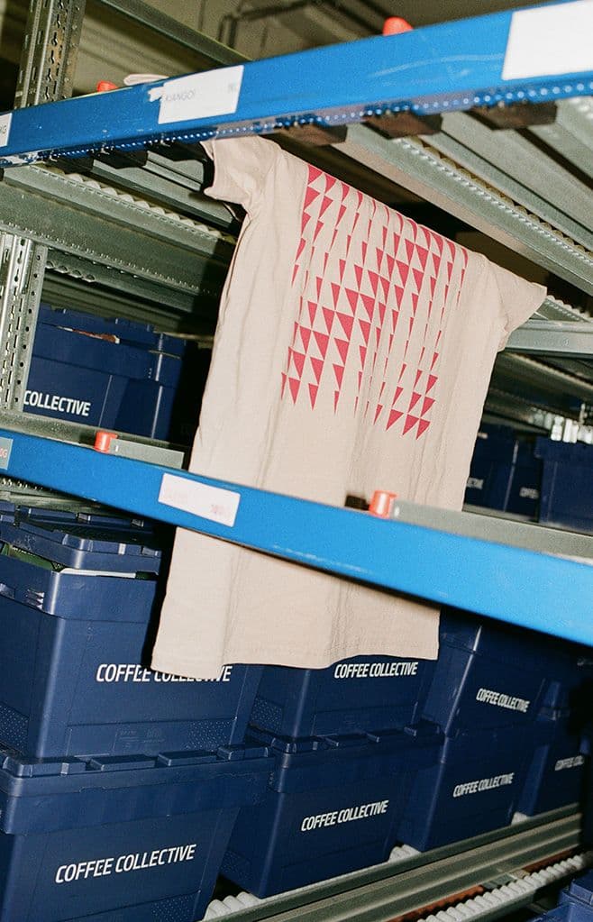 a t-shirt is hanging on a shelf next to boxes that say coffee collective